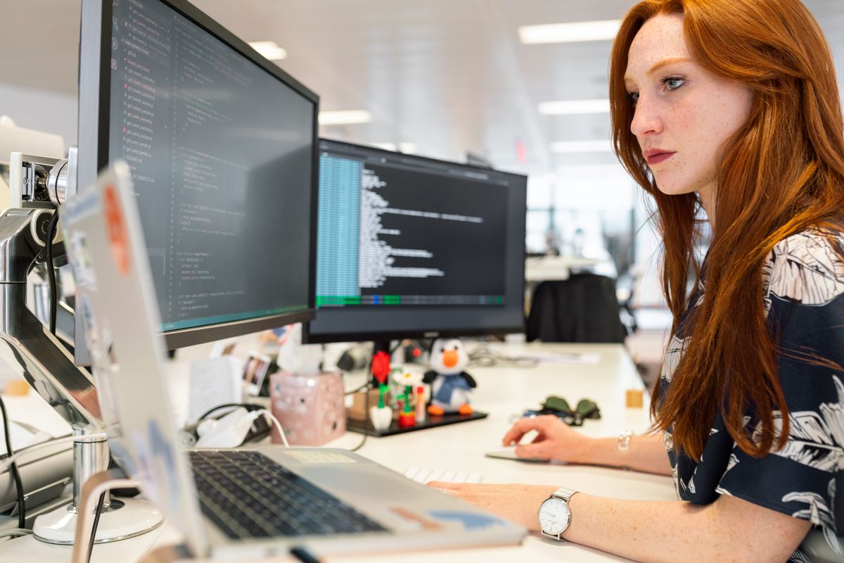 Cybersecurity analyst monitoring systems on multiple screens