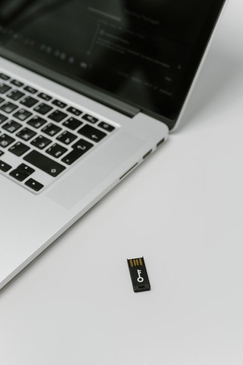 USB hardware security key on a desk beside a laptop